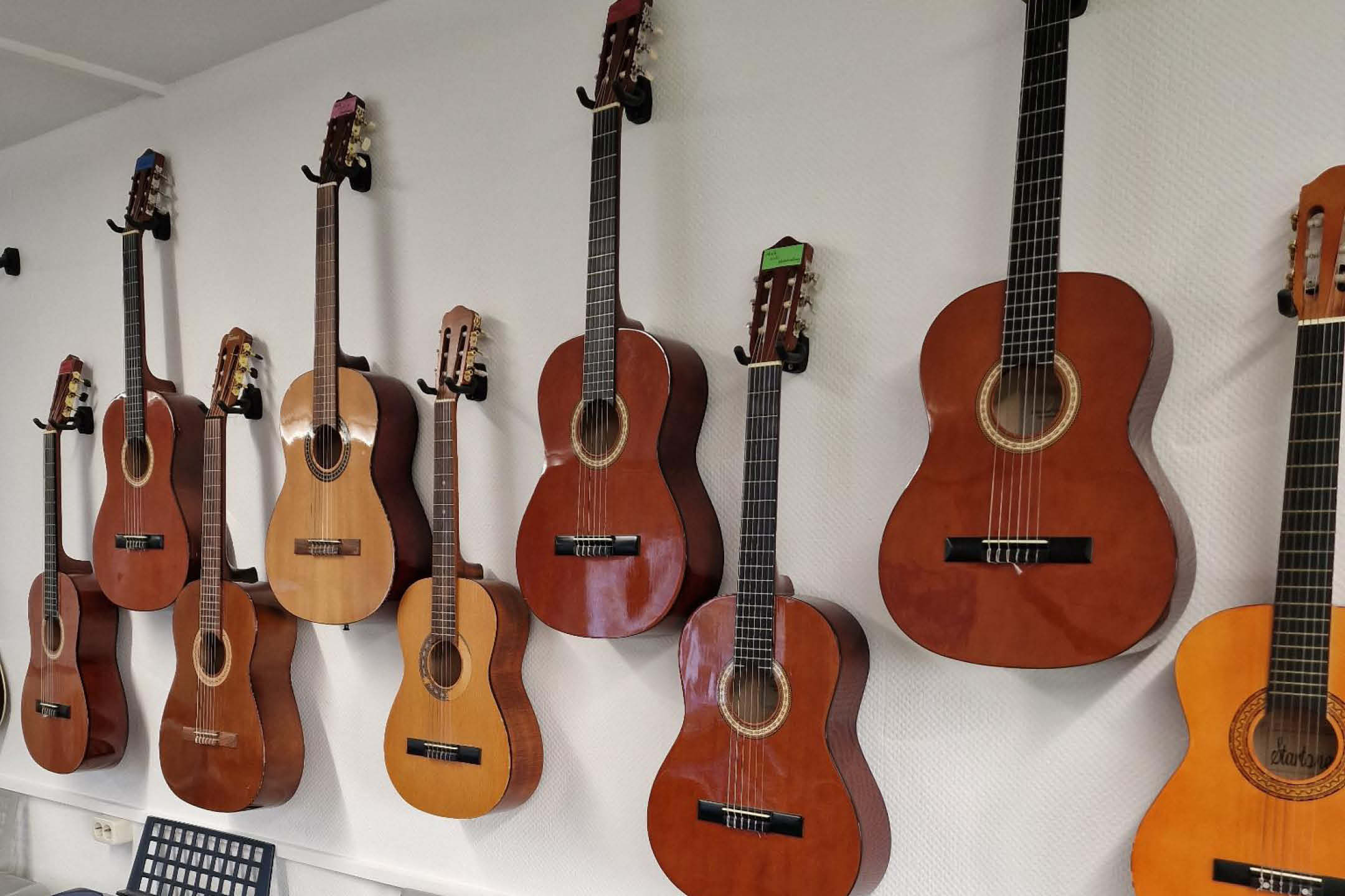 Ein Bild von einer Wand, an der 9 Gitarren hängen.