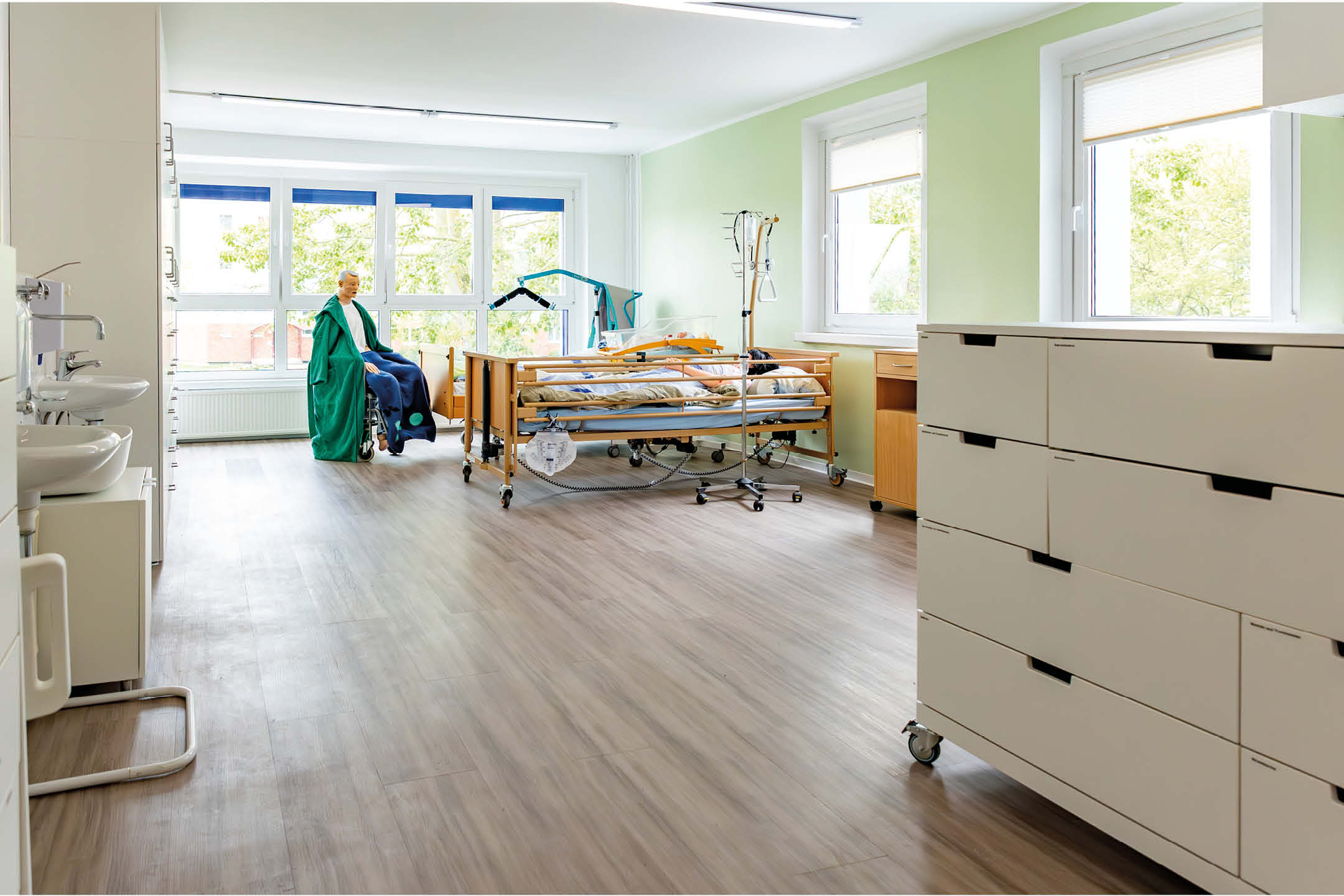 Ein Ausschnitt vom Pflegezimmer der bunta nach der Renovierung. Zu sehen sind Puppen in lebensechter Größe, Waschbecken und ein Multifunktionstisch.